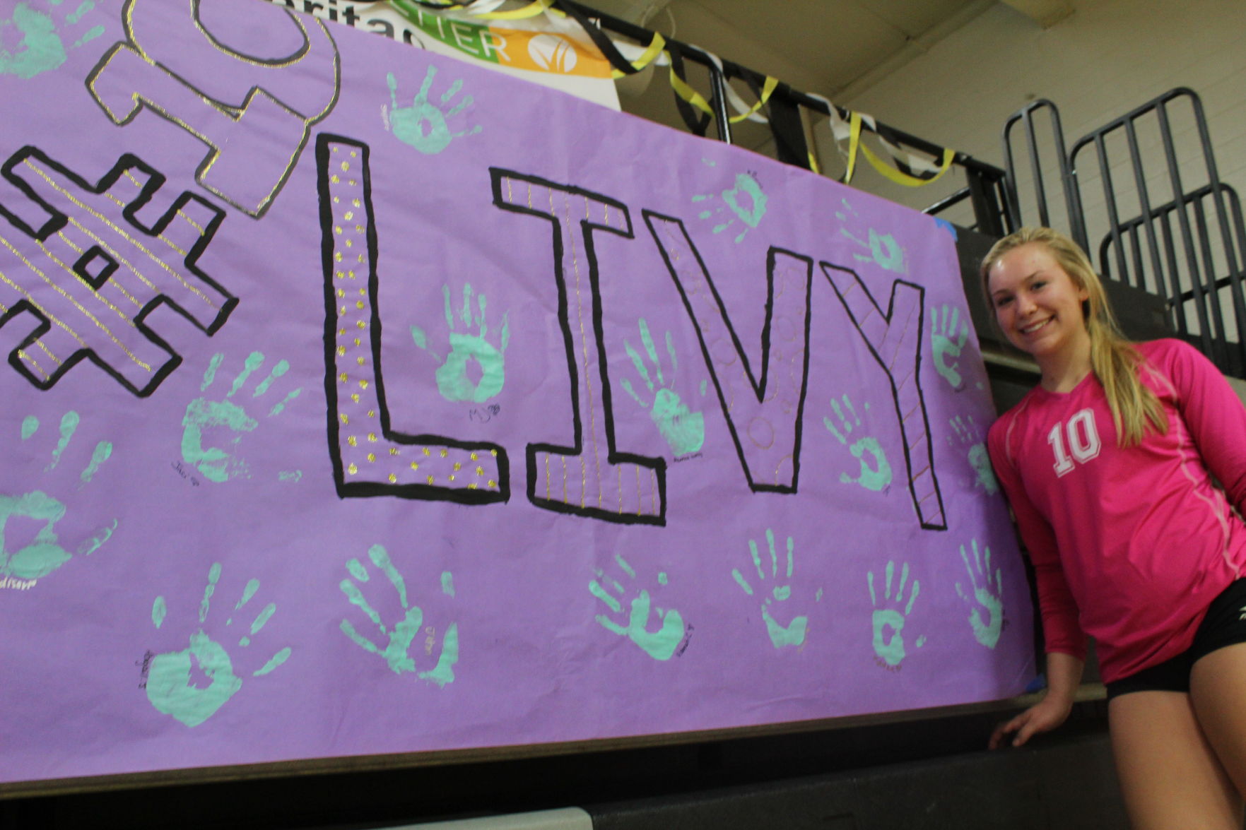 Livy Rich poses in front of her senior night sign